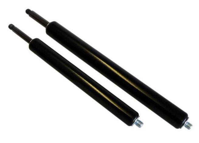 Sprężyny gazowe, Siłowniki gazowe | DAKAM Zdjęcie przedstawiające parę siłowników gazowych zainstalowanych w praktycznym zastosowaniu, np. przy dużej, ciężkiej klapie, bramie maszynowej lub pokrywie serwisowej. Siłowniki są zamocowane pod kątem, wyraźnie wspomagając podnoszenie i utrzymywanie klapy w pozycji otwartej. Otoczenie to hala produkcyjna lub przemysłowa maszyna (dominują szarości i metaliczne powierzchnie). Ujęcie demonstruje funkcjonalność sprężyn gazowych: ułatwianie obsługi, spowalnianie ruchu i bezpieczne utrzymywanie ciężaru.