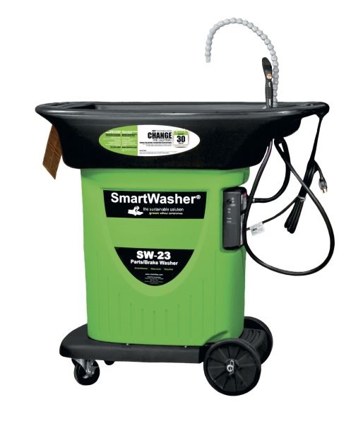 Jasne, ostre ujęcie studyjne przedstawiające myjkę biologiczną CRC SmartWasher, model SW-23. Urządzenie ma solidną, szarą lub czarno-szarą obudowę z wyraźnie widocznym stołem roboczym i kratownicą, na kt&oacute;rej kładzie się czyszczone części. Z tyłu myjki wznosi się kolumna z wężem i szczotką myjącą. Na przedniej części lub boku obudowy znajduje się panel sterowania z przyciskami oraz duży, widoczny napis "CRC SmartWasher SW-23". Kompozycja jest czysta i techniczna, podkreślając gotowość urządzenia do bezpiecznego, biologicznego czyszczenia części.