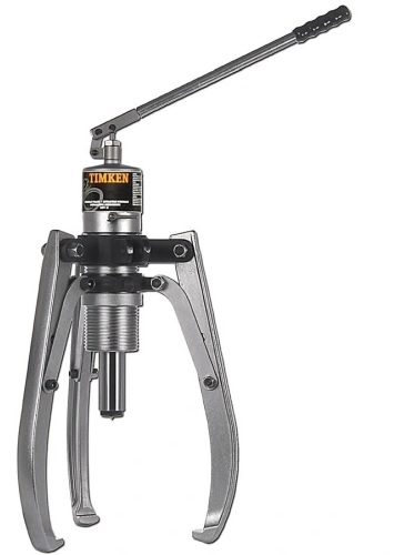 Obraz jest ucieleśnieniem amerykańskiej potęgi, bezpieczeństwa i profesjonalizmu w dziedzinie ciężkiego demontażu. Kompozycja prezentuje zestaw hydrauliczny TIMKEN VHPS (z oddzielną pompą i siłownikiem) jako kompletne rozwiązanie dla przemysłu. Całość łączy surową estetykę narzędzi premium z wizerunkiem autoryzowanego polskiego dystrybutora DAKAM, gwarantującego dostępność tego specjalistycznego sprzętu. W centrum uwagi, na czystej, metalowej powierzchni warsztatowej lub białym tle, znajduje się rozłożony, gotowy do pracy zestaw TIMKEN VHPS: &bull;	Masywny Siłownik: Centralnym punktem jest wolnostojący siłownik hydrauliczny (cylinder) z przelotowym otworem lub gwintem montażowym. Jego solidna, stalowa konstrukcja (często czerniona) wizualnie komunikuje zdolność do generowania potężnej siły (np. 20, 30 lub 50 ton). &bull;	Pompa z Manometrem: Obok siłownika stoi wysokowydajna pompa ręczna. Kluczowym elementem jest wyraźnie widoczny manometr, kt&oacute;ry symbolizuje precyzyjną kontrolę siły ściągania i bezpieczeństwo pracy. &bull;	Wąż Wysokociśnieniowy: Pompę i siłownik łączy solidny, zbrojony wąż hydrauliczny, wyposażony w szybkozłącza, co podkreśla mobilność i łatwość montażu zestawu. &bull;	Osprzęt (Ramiona/Trawersy): W tle zestawu widoczne są masywne elementy konstrukcyjne ściągacza &ndash; kute ramiona oraz głowica (trawers), kt&oacute;re po zmontowaniu z siłownikiem tworzą kompletne narzędzie. &bull;	Marka Premium: Na siłowniku oraz pompie widoczne jest wyraźne, oryginalne logo "TIMKEN", co jest gwarancją najwyższej jakości i trwałości. Tło jest subtelnie rozmyte (efekt bokeh), ale jednoznacznie wskazuje na profesjonalne zaplecze logistyczne: &bull;	Magazyn DAKAM: Widać zarysy regał&oacute;w wypełnionych solidnymi walizkami transportowymi (często z logo TIMKEN), w kt&oacute;rych te zestawy są przechowywane i dostarczane. &bull;	Logo Dystrybutora: W dyskretnym, ale widocznym miejscu (np. w rogu obrazu) umieszczone jest logo DAKAM, z dopiskiem "Autoryzowany Dystrybutor Narzędzi TIMKEN". Obraz niesie jasny komunikat: "Profesjonalne zestawy hydrauliczne TIMKEN z oddzielną pompą to gwarancja siły i bezpieczeństwa przy demontażu dużych łożysk i k&oacute;ł. DAKAM, jako autoryzowany dystrybutor, zapewnia dostępność tych zaawansowanych narzędzi w Polsce".